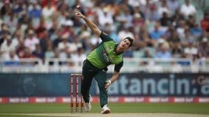 A professional cricketer bowling a delivery with focus